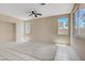 Open living room featuring neutral paint, tile and carpet flooring, multiple windows, and a ceiling fan at 9451 Natoma Station Pl, Las Vegas, NV 89123
