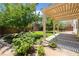 A beautifully landscaped backyard features a covered patio, lush trees, and verdant green lawn at 1371 Cumulus Ct, Henderson, NV 89014