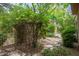 Backyard view with stone walkway leading to a stone outdoor fireplace surrounded by lush plants and trees at 15 Emerald Dunes Cir, Henderson, NV 89052