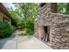 Close-up of stone outdoor fireplace with firewood, surrounded by lush greenery for cozy ambiance at 15 Emerald Dunes Cir, Henderson, NV 89052