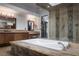Beautiful main bathroom with a soaking tub surrounded by stone, vanities, and a glass shower enclosure at 17 Soaring Bird Ct, Las Vegas, NV 89135