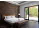 Bright bedroom with a stone accent wall and sliding doors that lead to a balcony at 17 Soaring Bird Ct, Las Vegas, NV 89135
