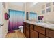 Bathroom with dual sinks, wood cabinets, granite counters, and stylish shower curtain at 2079 Port Royal Dr, Laughlin, NV 89029