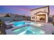 Backyard features a modern pool and hot tub with ambient lighting and an outdoor patio area with backyard kitchen at 2833 Sangro Ct, Henderson, NV 89044