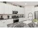 Close up of kitchen featuring white cabinets, black marble countertops and backsplash, and stainless steel appliances at 2833 Sangro Ct, Henderson, NV 89044