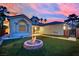 Backyard view highlighting a fire pit with flames, manicured artificial turf, and desert landscaping at 5509 Rose Thicket St, Las Vegas, NV 89130