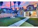 Cozy backyard features a fire pit, green artificial turf, and palm trees against a colorful sunset at 5509 Rose Thicket St, Las Vegas, NV 89130