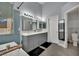 Bright bathroom with double sinks, gray cabinets, walk-in shower, and soaking tub with modern fixtures at 5509 Rose Thicket St, Las Vegas, NV 89130