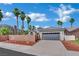 Well-maintained exterior with a gray two-car garage, desert landscaping, and mature palm trees at 5509 Rose Thicket St, Las Vegas, NV 89130