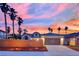 House with a two-car garage, desert landscaping, and palm trees, against a colorful sunset backdrop at 5509 Rose Thicket St, Las Vegas, NV 89130