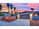 Spacious two-car garage and paved driveway under a vibrant sunset, surrounded by palm trees at 5509 Rose Thicket St, Las Vegas, NV 89130