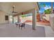 Covered patio with a ceiling fan overlooking the pool and a lushly landscaped backyard with mature palm trees at 5509 Rose Thicket St, Las Vegas, NV 89130