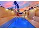A backyard pool sparkles under festive string lights and a vibrant sunset sky at 5509 Rose Thicket St, Las Vegas, NV 89130