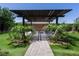Landscaped backyard featuring a pergola with fire pit, synthetic grass, and mature palm trees at 5761 E Badlands Ln, Pahrump, NV 89061