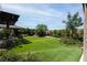 Backyard featuring lush landscaping, synthetic lawn, and mature trees at 5761 E Badlands Ln, Pahrump, NV 89061