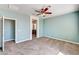 Well-lit bedroom with neutral carpet, aqua walls, ceiling fan, and doorway to an en suite bathroom at 6808 Mystic Plain Ct, Las Vegas, NV 89149