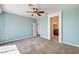 Spacious bedroom with neutral carpet, aqua walls, ceiling fan, and doorway to an en suite bathroom at 6808 Mystic Plain Ct, Las Vegas, NV 89149