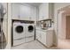 Well-organized laundry room with white cabinetry, sink, and modern washer/dryer units at 8928 Stafford Springs Dr, Las Vegas, NV 89134