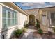 Inviting front entrance with an arched doorway, desert landscaping and shuttered windows at 10240 Notte Ave, Las Vegas, NV 89135