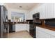 Kitchen with granite countertops, white cabinets, black appliances, and a pass-through window to the outdoor dining area at 10240 Notte Ave, Las Vegas, NV 89135
