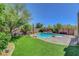 Lush backyard featuring a pool, spa, artificial turf and comfortable seating area, creating a private retreat at 10656 Hyde Corner Ave, Las Vegas, NV 89166