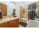 Cozy bathroom featuring wood cabinets, tan tile shower/tub, and neutral colored walls and flooring at 11 Knob Oak Dr, Henderson, NV 89052