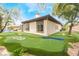 A rear view of a house with a backyard putting green and mature trees at 11 Knob Oak Dr, Henderson, NV 89052
