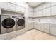 Well-organized laundry room with cabinetry, counter space, geometric tile backsplash, and stainless steel washer/dryer at 11 Knob Oak Dr, Henderson, NV 89052