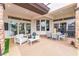 A covered patio with travertine floors features a dining table, seating area, and outdoor kitchen at 11 Knob Oak Dr, Henderson, NV 89052