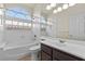Bright bathroom featuring a tub with glass block window, dark vanity, and tiled flooring at 11056 Kilkerran Ct, Las Vegas, NV 89141