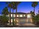 Elegant two-story home at dusk featuring a three-car garage, palm trees, and a well-manicured front yard at 11056 Kilkerran Ct, Las Vegas, NV 89141