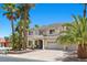 Charming two-story home boasts a three-car garage, a covered entrance, and is surrounded by swaying palm trees at 11056 Kilkerran Ct, Las Vegas, NV 89141