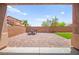 View of the backyard with brick patio and seating area, enclosed by a brick wall and glimpses of neighboring houses at 11274 Civita St, Las Vegas, NV 89141