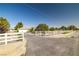 Property featuring a long white fence, an ample driveway, and mature trees dotting the landscape at 170 Dove St, Pahrump, NV 89060
