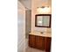Bathroom vanity features a white countertop, wood cabinetry, framed mirror and decorative lighting at 1830 N Buffalo Dr # 1010, Las Vegas, NV 89128