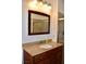 Bathroom vanity with granite countertop, wood cabinets, framed mirror, and accent lighting at 1830 N Buffalo Dr # 1010, Las Vegas, NV 89128