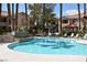 Community pool with a water feature surrounded by lounge chairs and tropical landscaping at 1830 N Buffalo Dr # 1010, Las Vegas, NV 89128