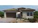 Stylish single-story home featuring a tile roof, stone accents, desert landscaping, and a two-car garage at 214 Piazzetta Pl, Henderson, NV 89011