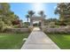 Elegant community entrance with stone architecture, lush landscaping, and manicured lawns under a sunny sky at 42 Ravenswood Ave, Las Vegas, NV 89141