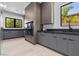 Well-equipped laundry room with gray cabinetry, sleek black appliances, stone countertops, and natural light from windows at 42 Ravenswood Ave, Las Vegas, NV 89141
