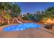 Sparkling swimming pool with a slide, surrounded by lush landscaping at twilight at 4737 Barcelona Ridge Ct, Las Vegas, NV 89129