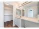 Bright bathroom with a large mirror, white cabinets, and wood-style flooring with a walk in closet at 5340 Santa Fe Heights St, North Las Vegas, NV 89081