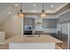 A modern island kitchen features pendant lighting, granite countertops, and sleek gray cabinetry at 646 Spotted Falcon St, Las Vegas, NV 89138
