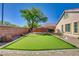 Backyard putting green surrounded by mature shade tree, block wall, rock landscaping and tile roof at 6656 Arctic Breeze St, North Las Vegas, NV 89084