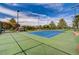 Well-maintained tennis court with green and blue surface, surrounded by trees and landscaping, perfect for recreation at 6656 Arctic Breeze St, North Las Vegas, NV 89084