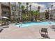 This community pool is surrounded by palm trees, lounge chairs, and outdoor seating areas at 7155 S Durango Dr # 303, Las Vegas, NV 89113
