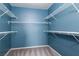 A walk-in closet featuring built-in white shelving on blue walls with neutral carpet at 7155 S Durango Dr # 303, Las Vegas, NV 89113