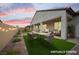 Staged covered back patio with artificial grass, string lights, and dining and seating furniture at 717 Monroe Hill Pl, Henderson, NV 89011