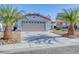 Beautiful single-story home with a two-car garage, driveway, and lush palm tree landscaping at 7405 Saybrook Point Dr, Las Vegas, NV 89128