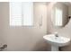 Cozy powder room featuring pedestal sink, oval mirror, and white window blinds at 8860 Hampton Green Ave, Las Vegas, NV 89129